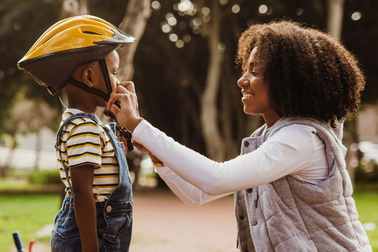 Woman fastening child's helmet.